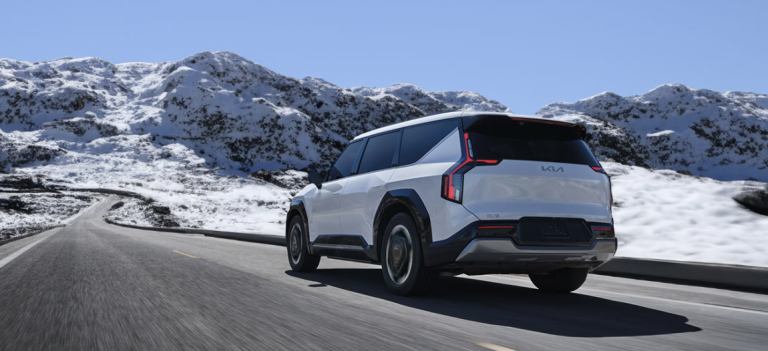 white kia ev9 driving on snowy highway